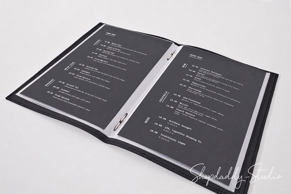 An open black ring binder menu folder with printed white text on both pages, photographed on a clean white background. A Shoplady Studio watermark is visible in the lower right corner.