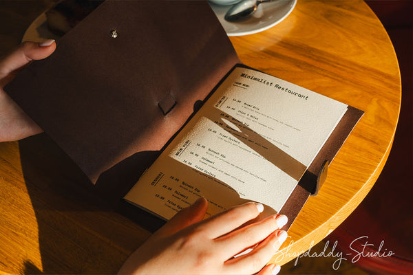 dark brown leather menu cover with elastic bands securing the pages inside