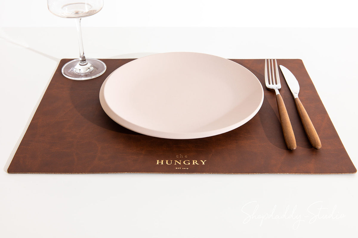 Antique brown recycled leather table placemat adding a rustic touch to dining decor.