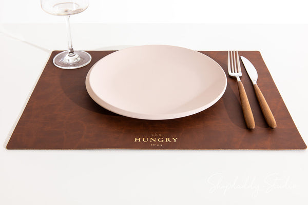 Antique brown recycled leather table placemat adding a rustic touch to dining decor.