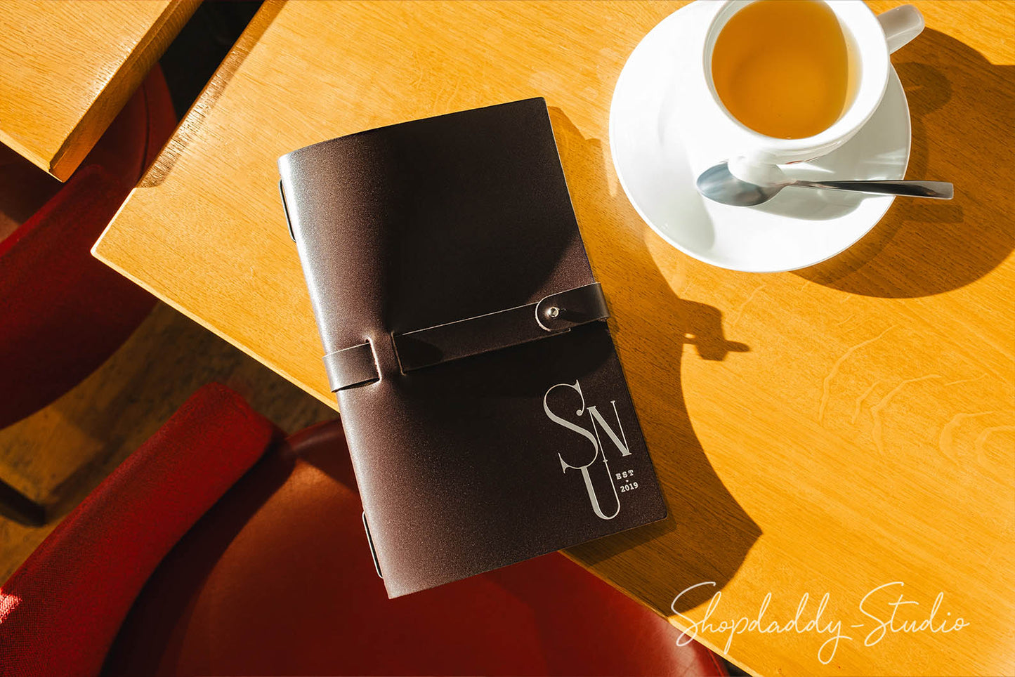 Dark brown thick leather menu cover with a minimalist belt strap, exuding timeless sophistication