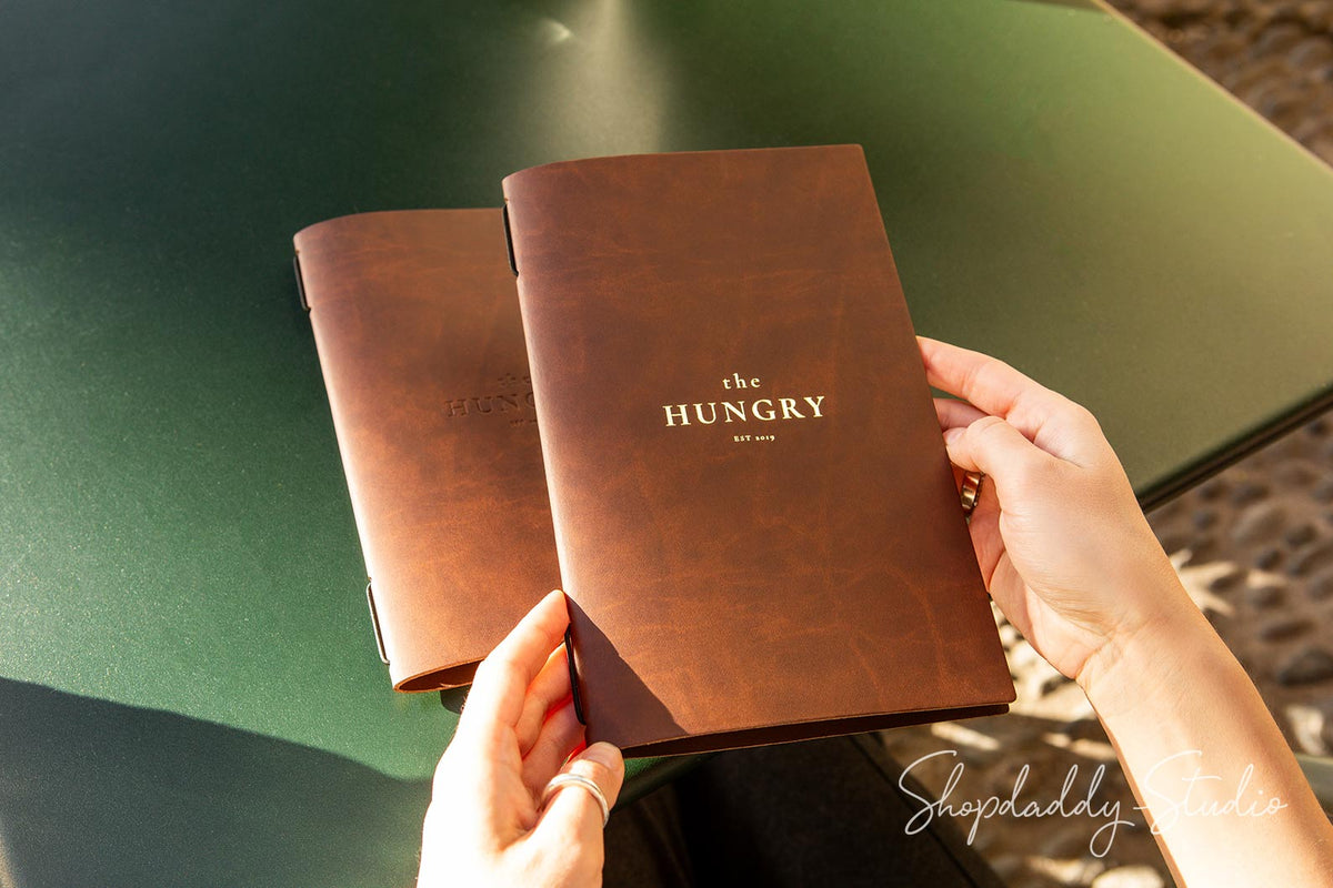 Elegant antique brown leather menu cover with a secure elastic band for papers.
