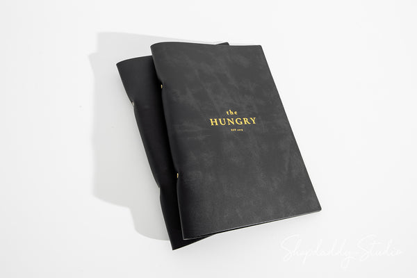 Modern menu cover shown in upscale hospitality interior