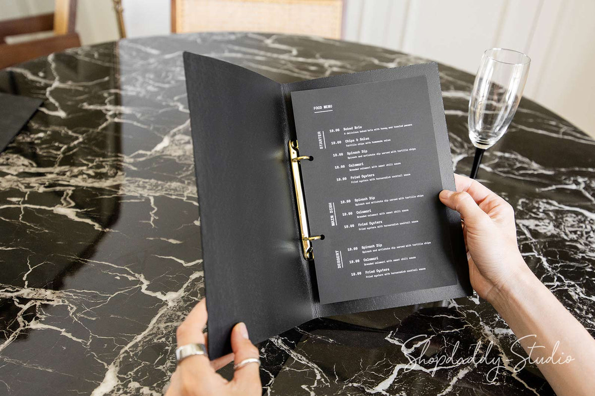 Open leather menu folder showing inserted menu pages in binder rings