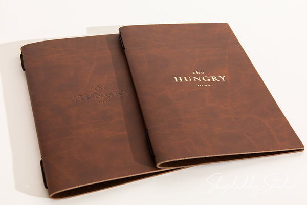 Minimalist menu cover in recycled leather with elastic band, ideal for cafes.